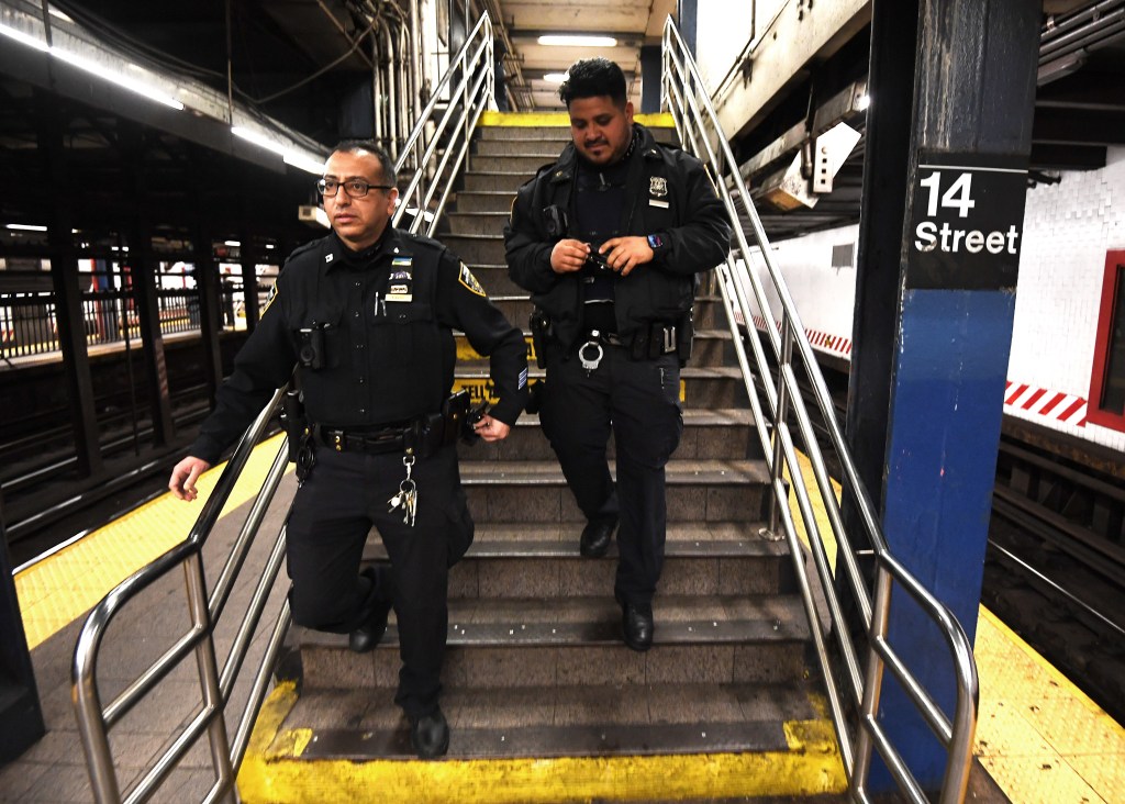 Two police officers walking down subway stairs at the 14th Street Union Square station.