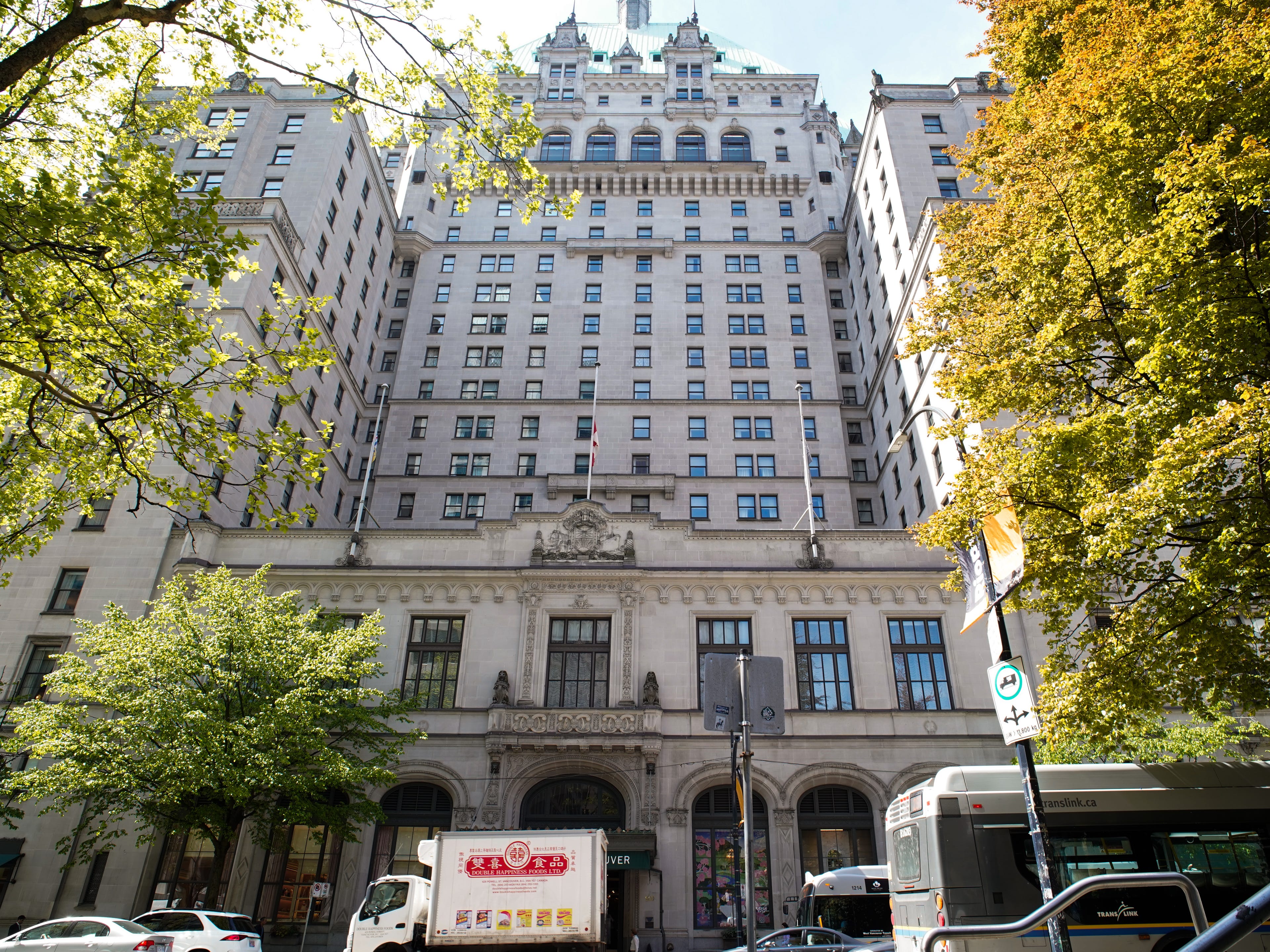 The exterior of the castle-like Fairmont Hotel Vancouver with trees on either side