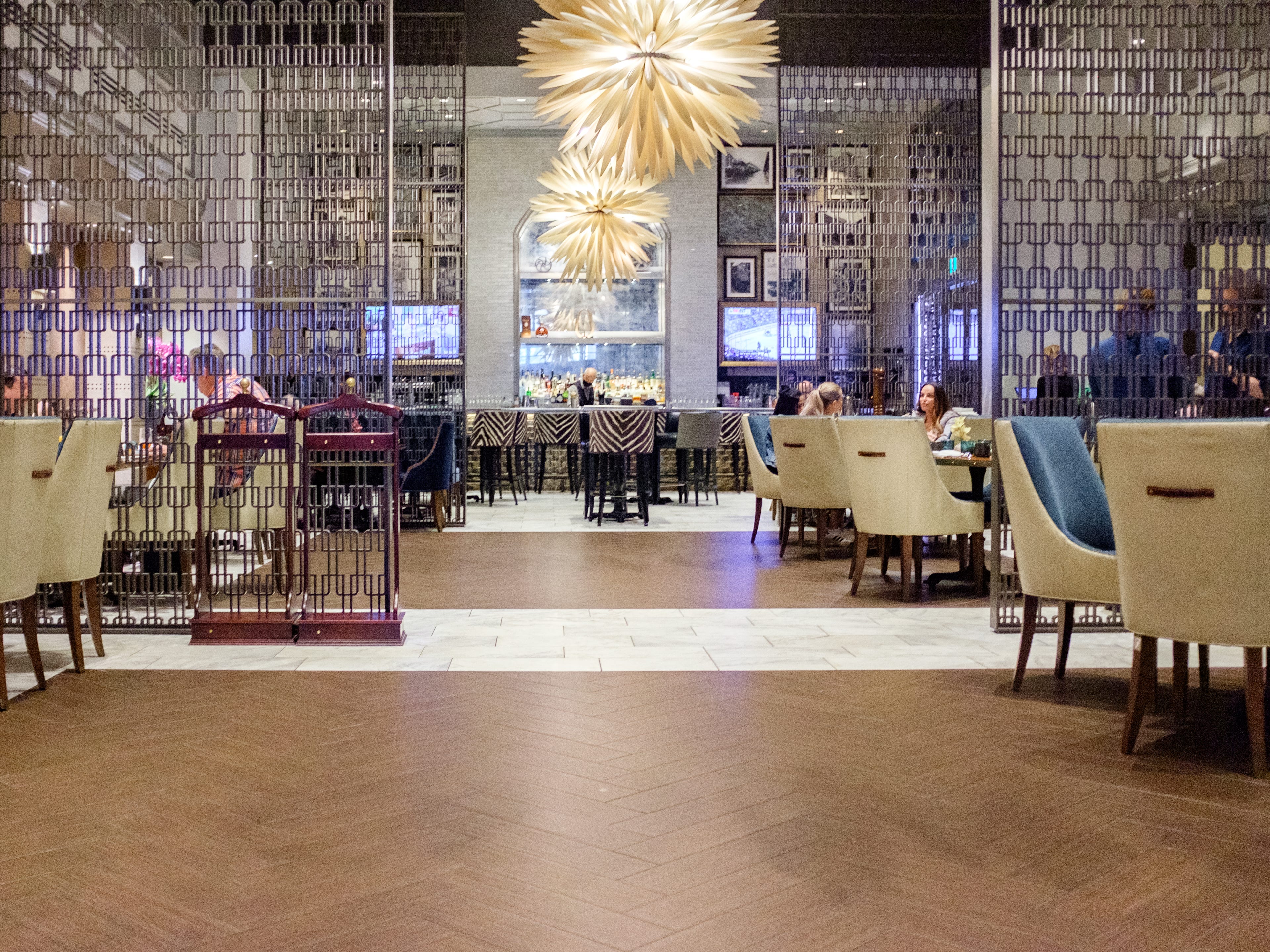 A restaurant inside the Fairmont Hotel Vancouver with large chandeliers and a bar at the back