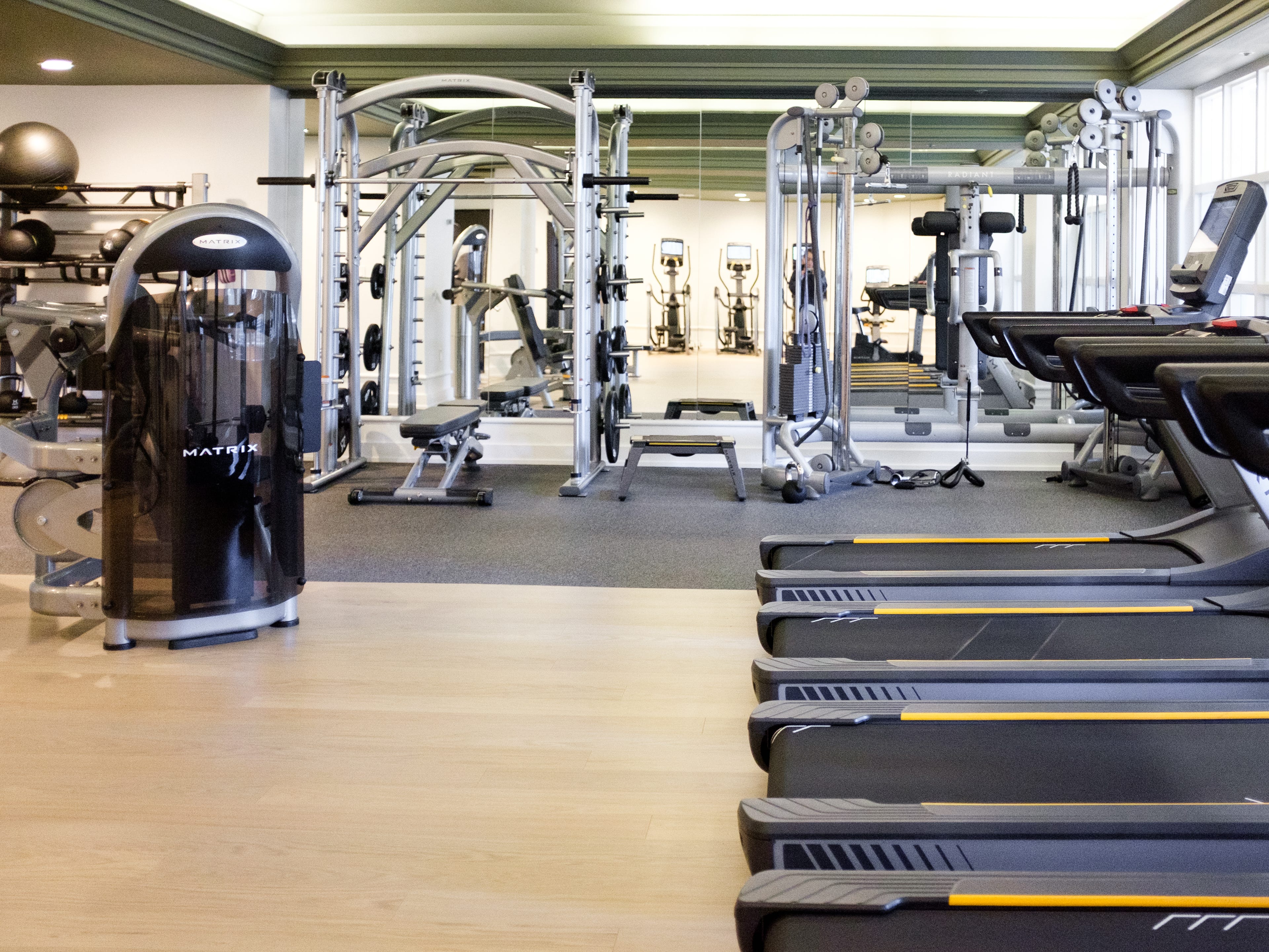Inside an empty hotel gym with treadmills on the right and strength training equipment on the left