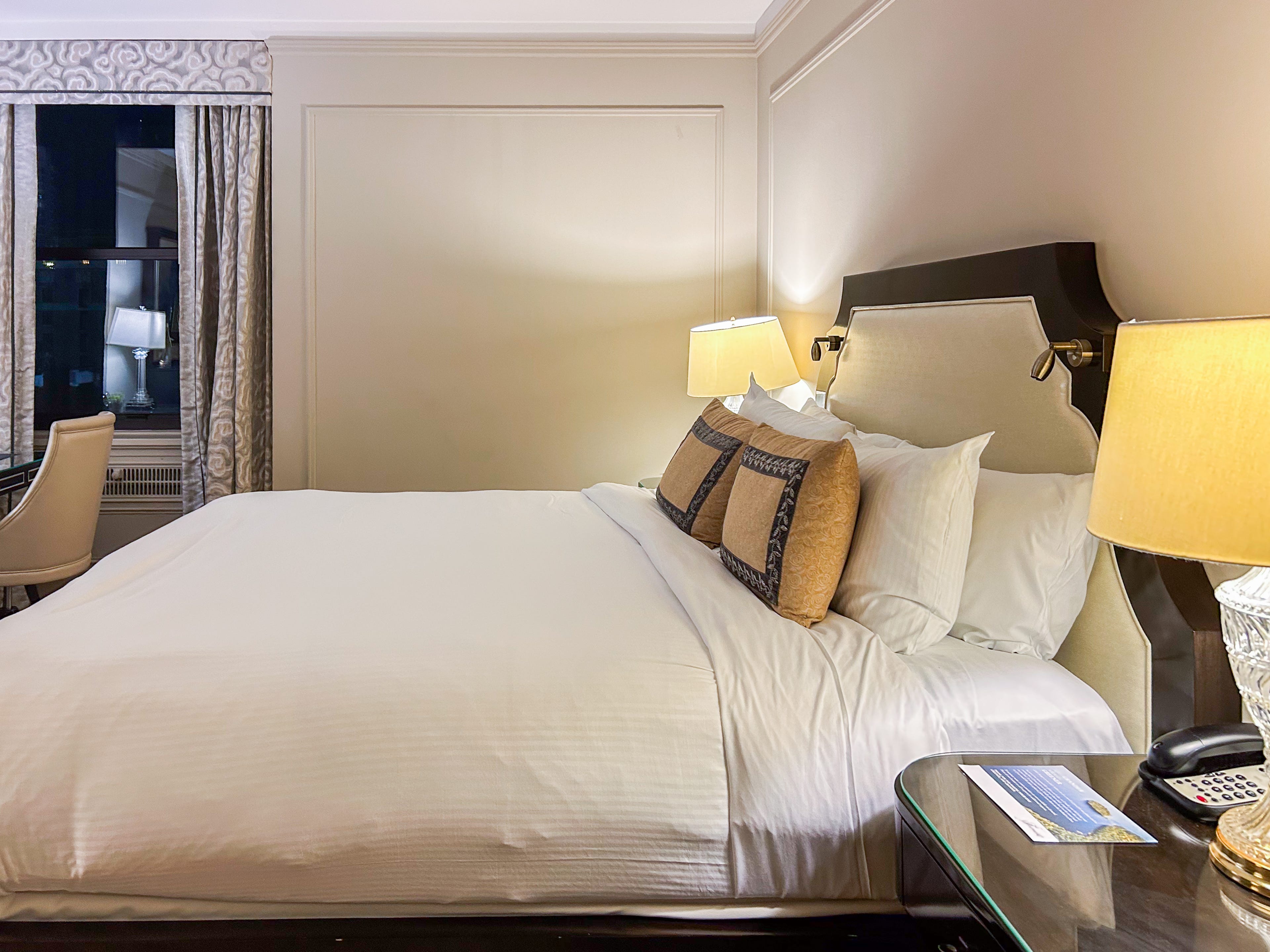 Inside a hotel room with a bed between two nightstands and a window on the left