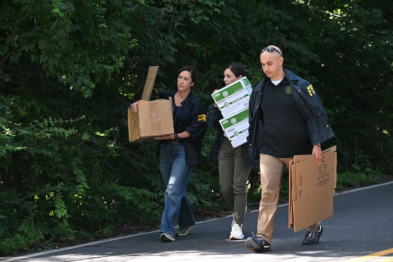 FBI agents carry boxes as they exit John Bolton's house, Donald Trump's former national security advisor after the FBI conducted a court-authorized search at his place on August 22, 2025 in Bethesda, Maryland.
