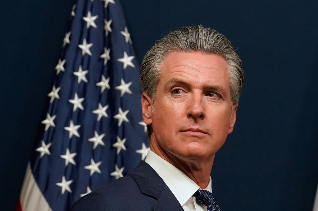 California Governor Gavin Newsom speaking in front of an American flag.