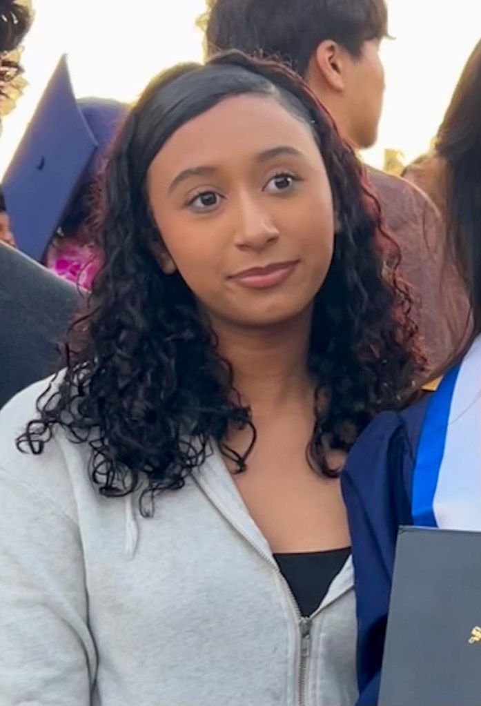 A headshot of Celeste Rivas, a young woman with dark curly hair and a light grey hoodie.