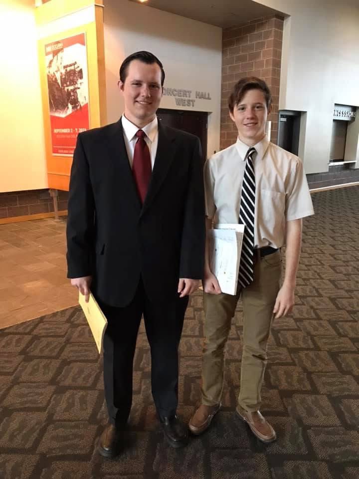 Lance Twiggs standing with Tyler Robinson, dressed in a suit and tie.