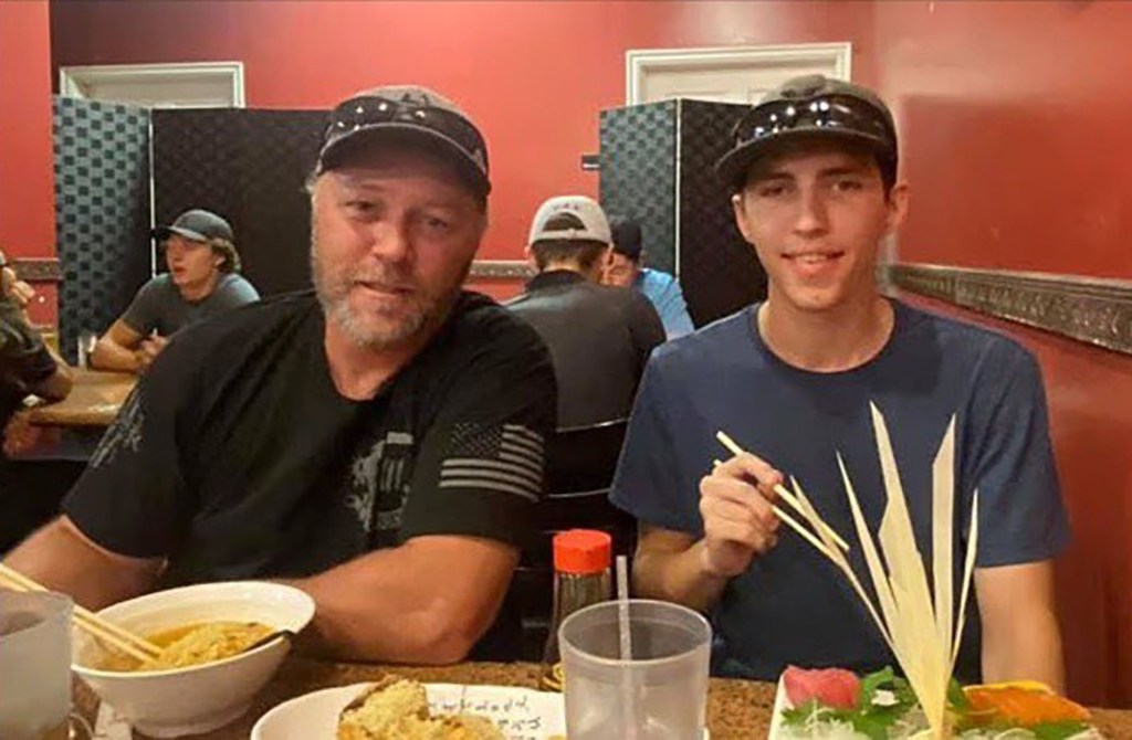 Tyler Robinson eating with an older man, both wearing baseball caps.