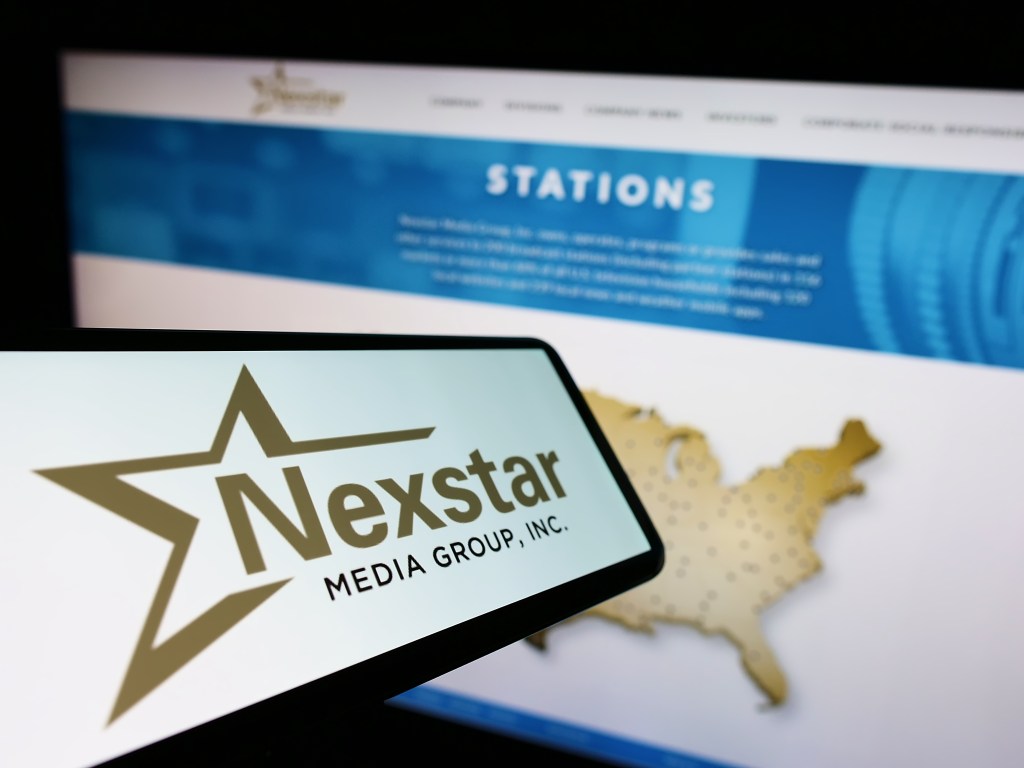 Smartphone displaying the Nexstar Media Group Inc. logo in front of a website with a map of the United States.
