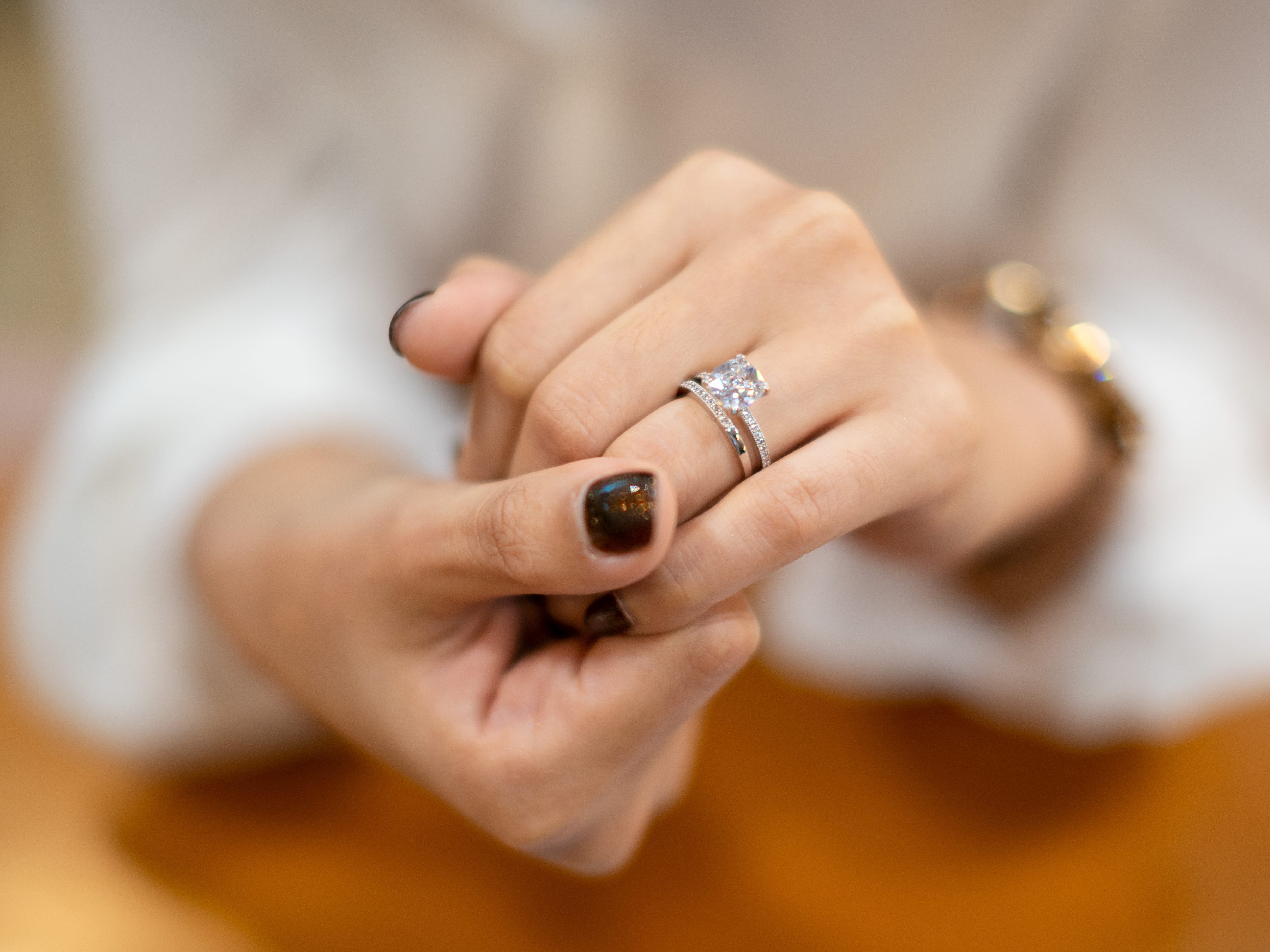 An engagement ring and wedding band on a hand. Both are covered in small diamonds.