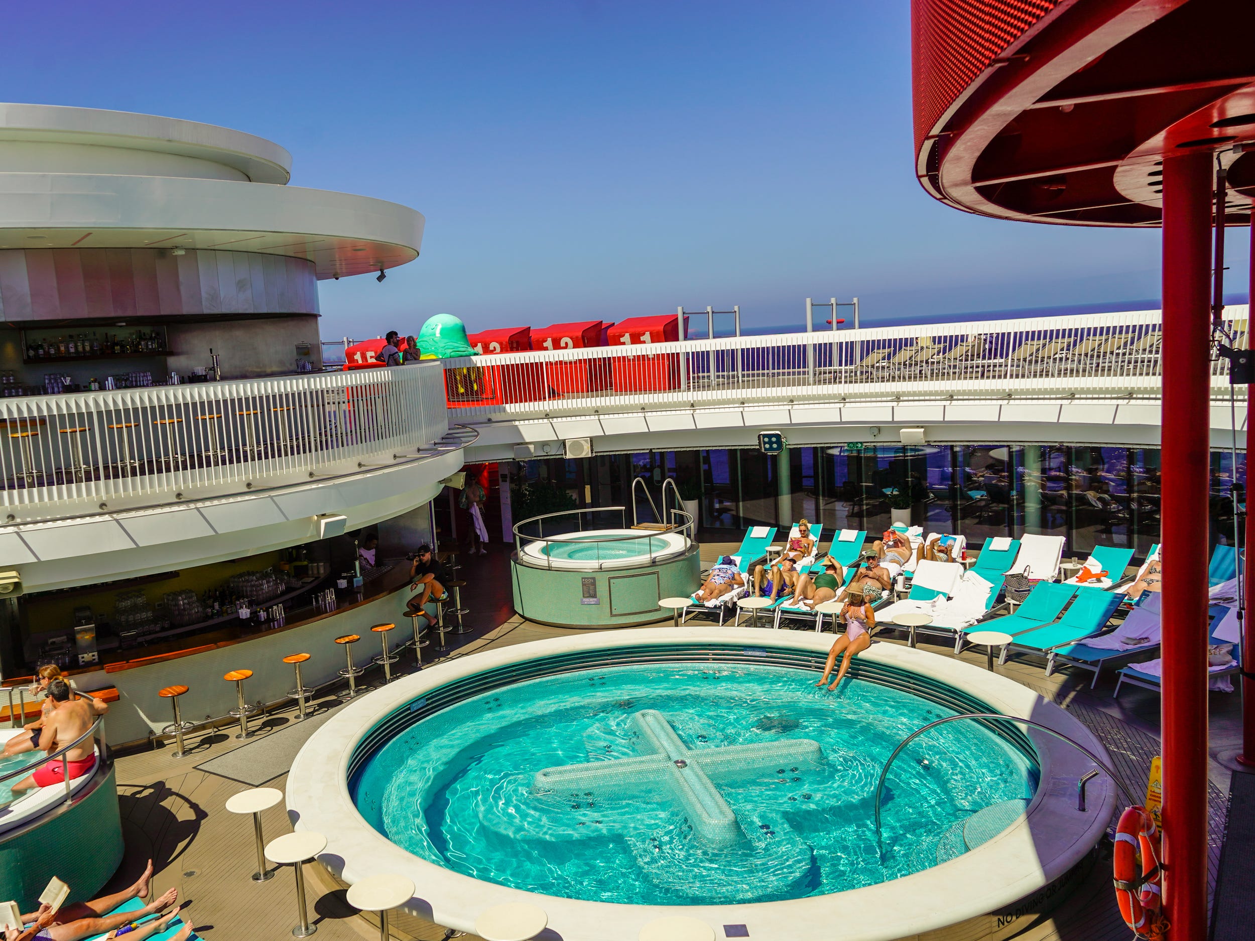 A pool on a cruise ship with a few passengers relaxing