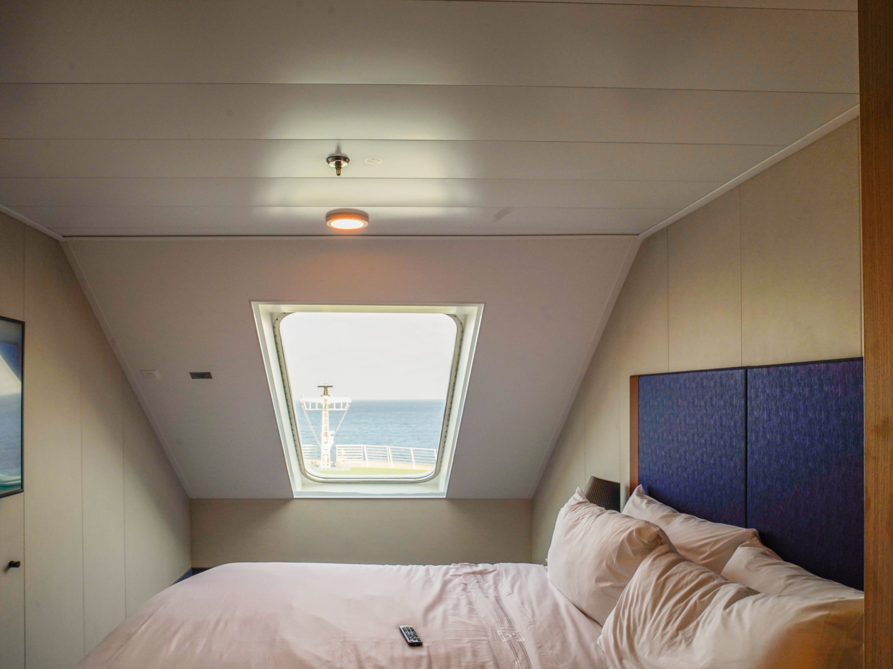 A cruise ship cabin with a window in front of the bed