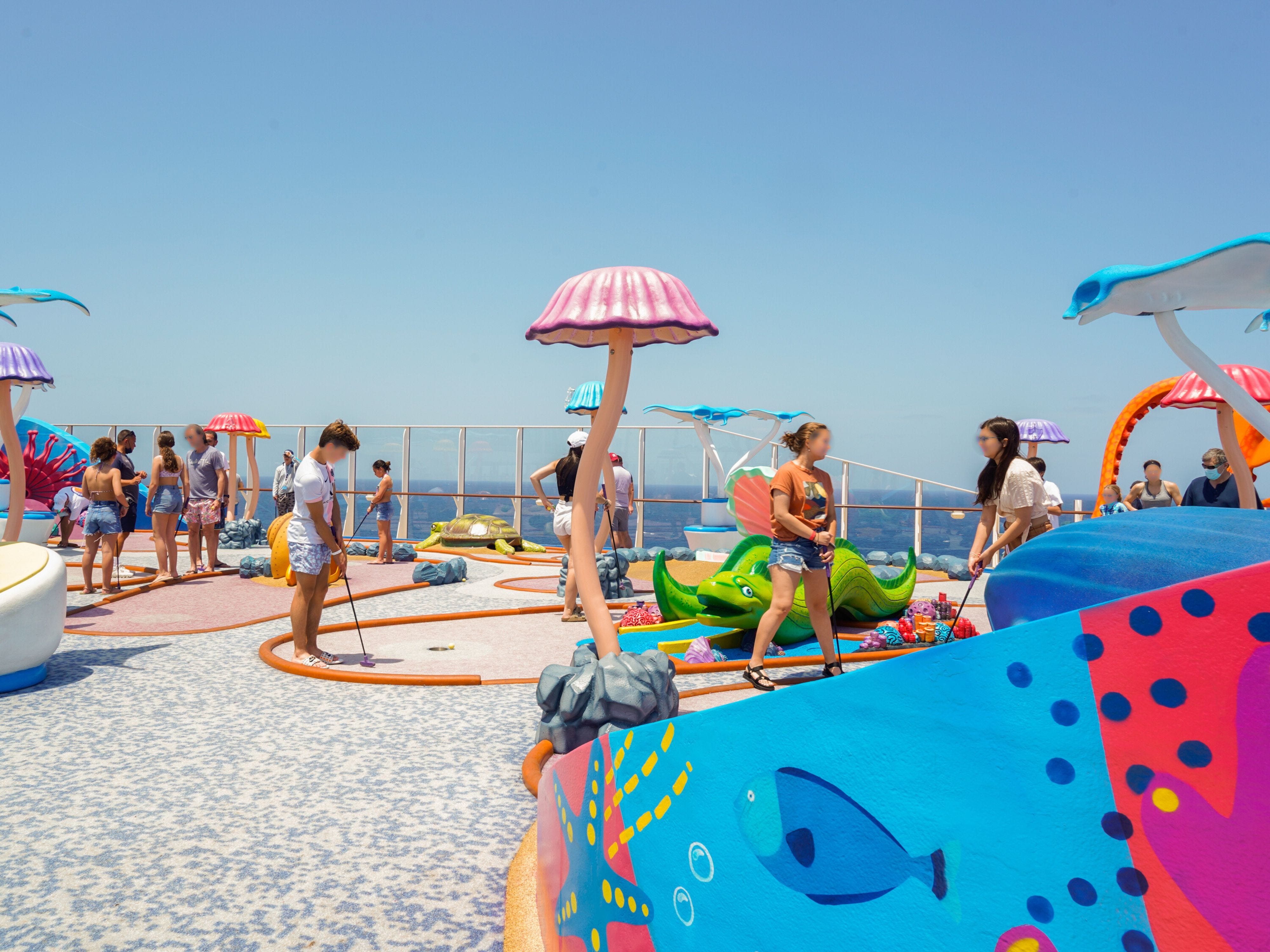 Young cruise passengers play mini golf on the top deck of a cruise ship.