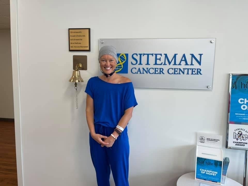 Woman posing next to cancer bell