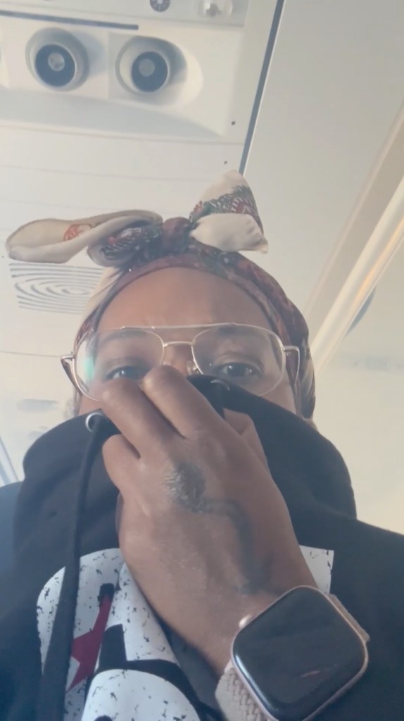 A passenger covering their mouth and nose in a hazy airplane cabin.