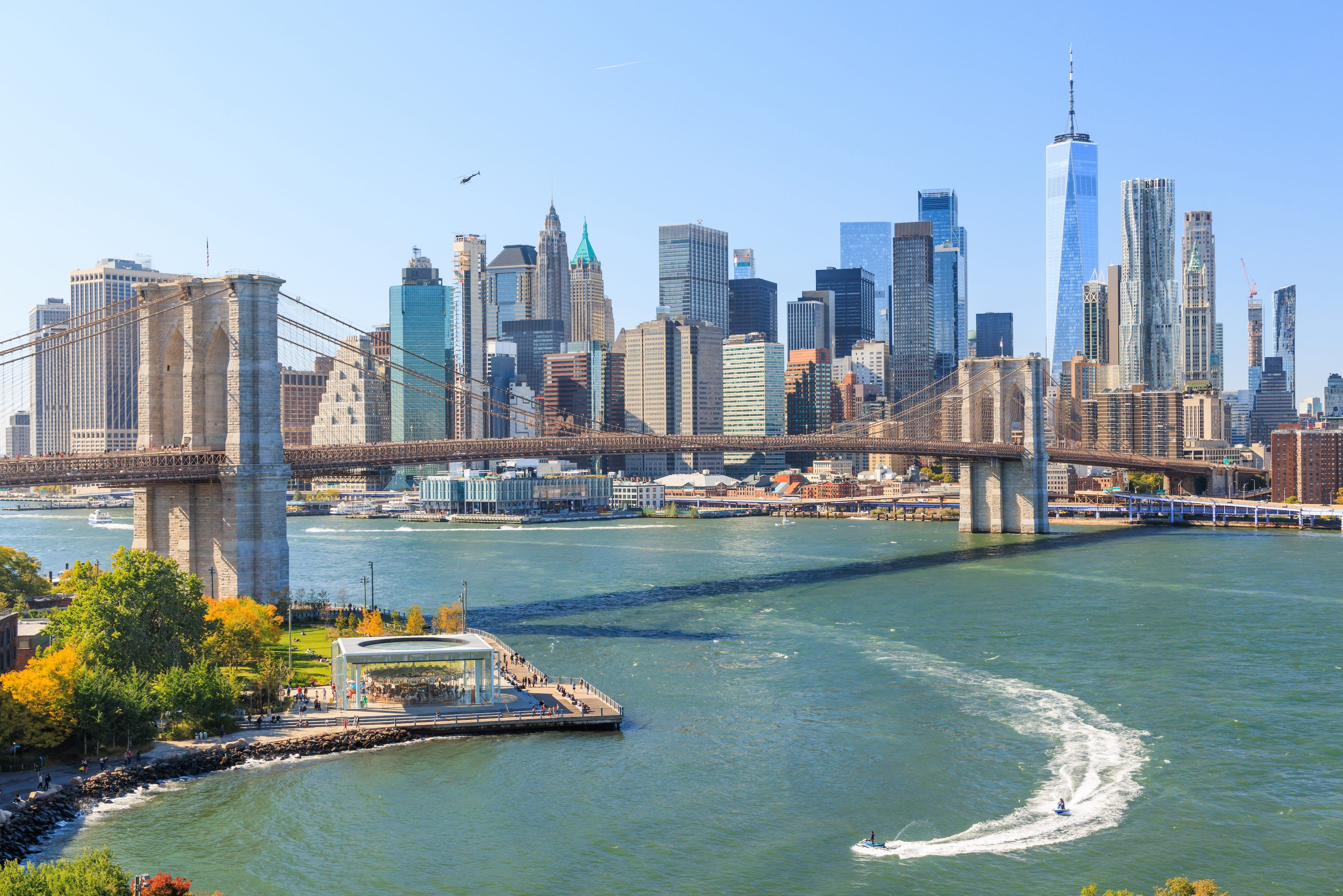 A view of the New York City skyline with the Brooklyn Bridge in the middle ground.