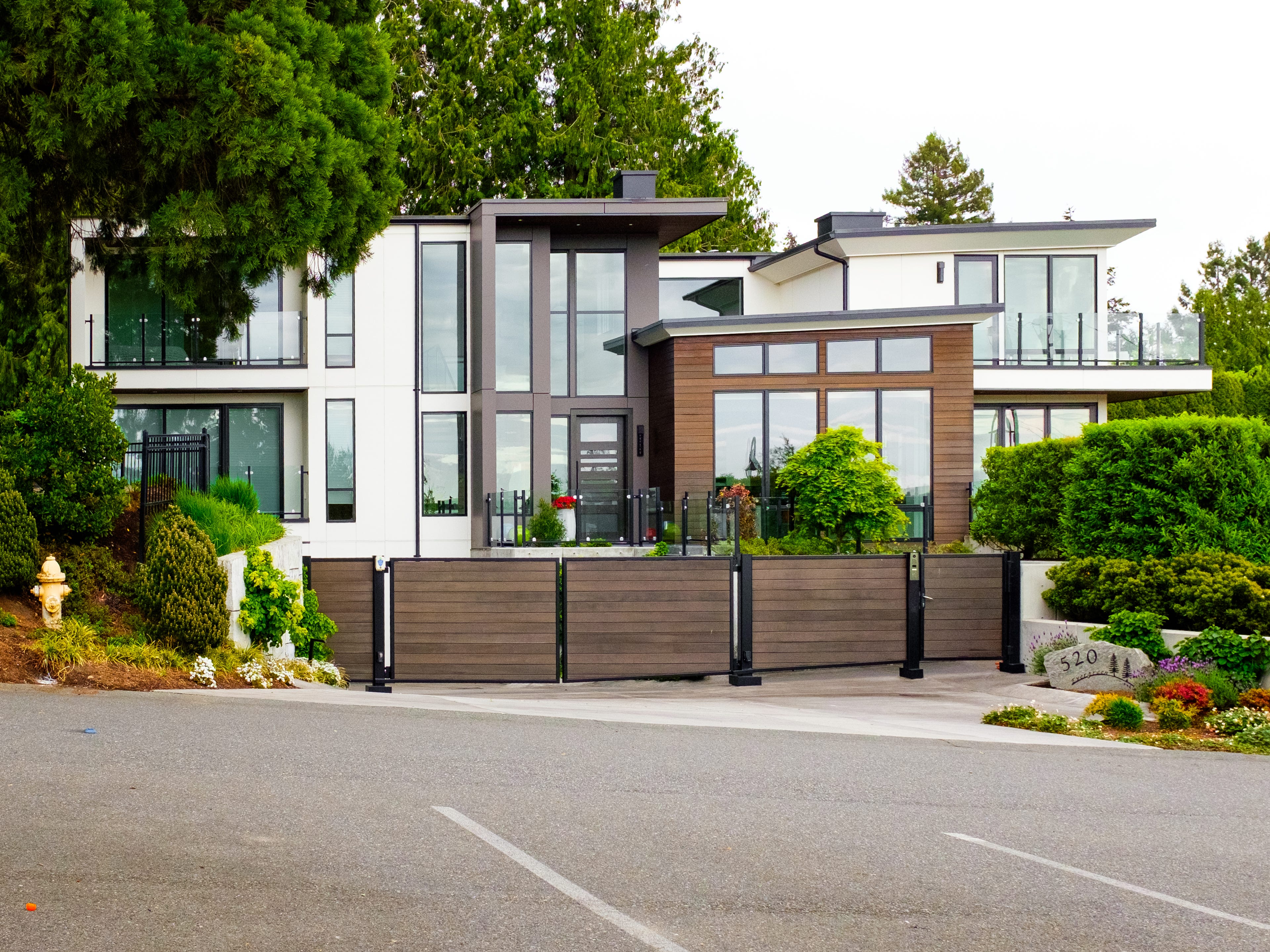A modern, luxury home in Medina, Washington, with bushes in the front and trees behind