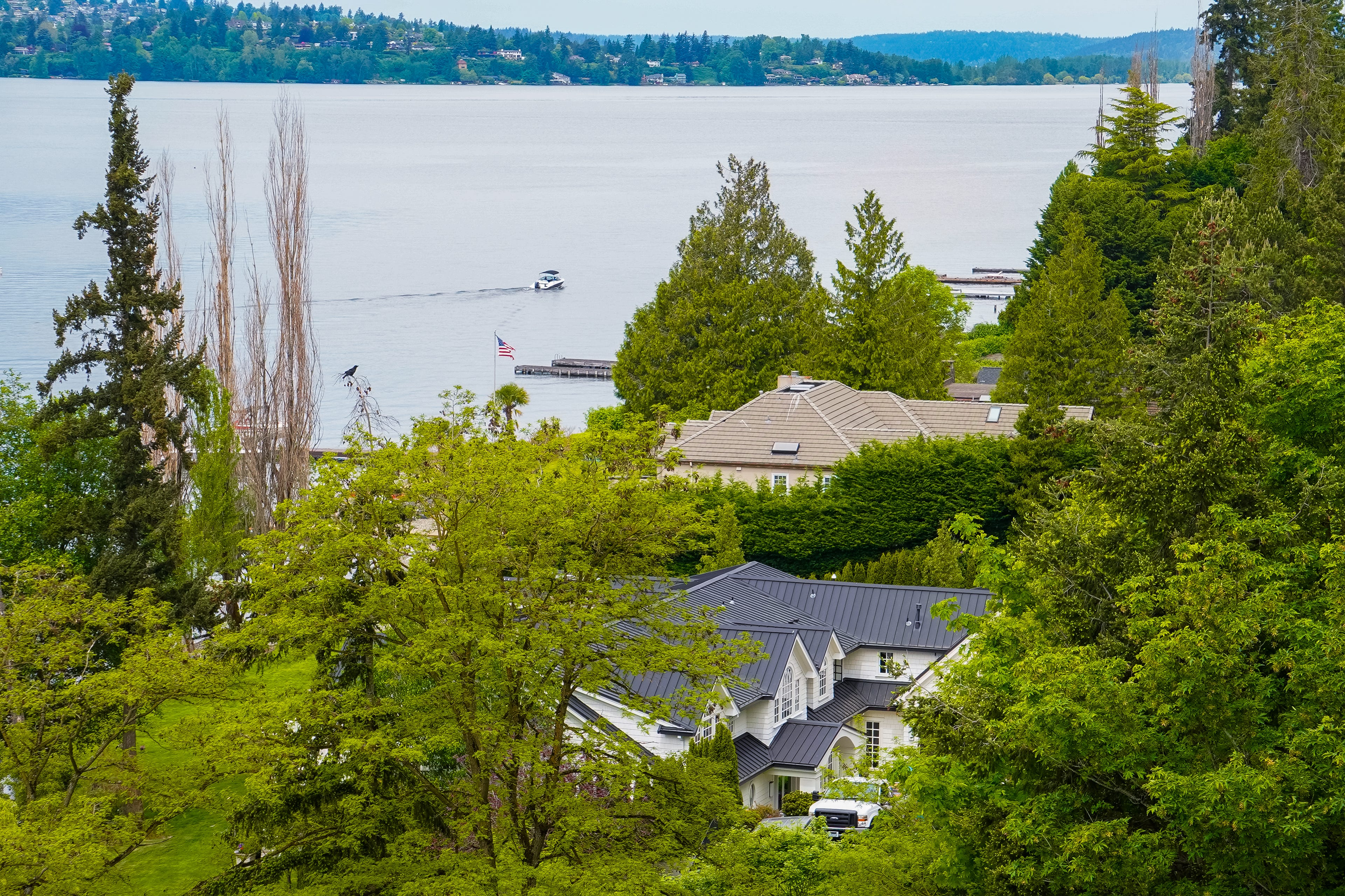 In Medina, Washington, Large homes are hidden between trees with a body of water and hills in the background