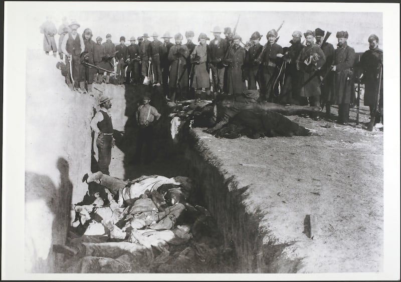 Soldiers and civilians watch while the bodies of Lakota are dumped into a mass grave hacked into the frozen Dakota soil after the massacre at Wounded Knee, South Dakota, USA, December 1890.