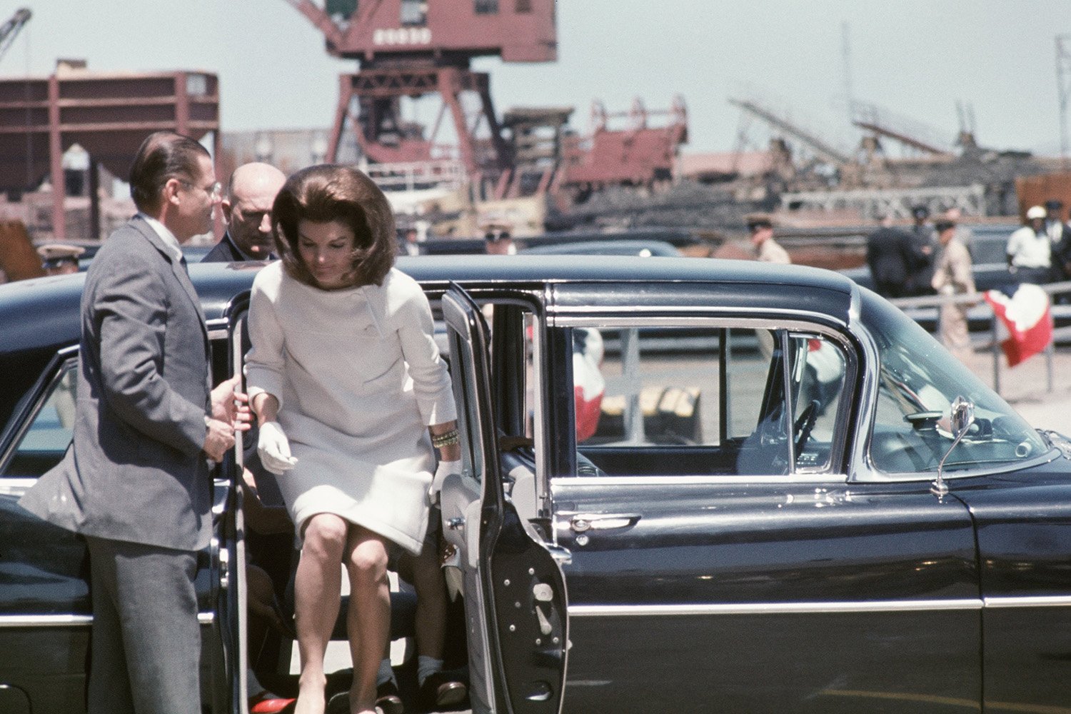 Secretary of Defense Robert McNamara helps former First Lady Jacqueline Kennedy out of her car before a ceremony to christen the USS John F. Kennedy on May 27, 1967, in Newport News, Virginia.