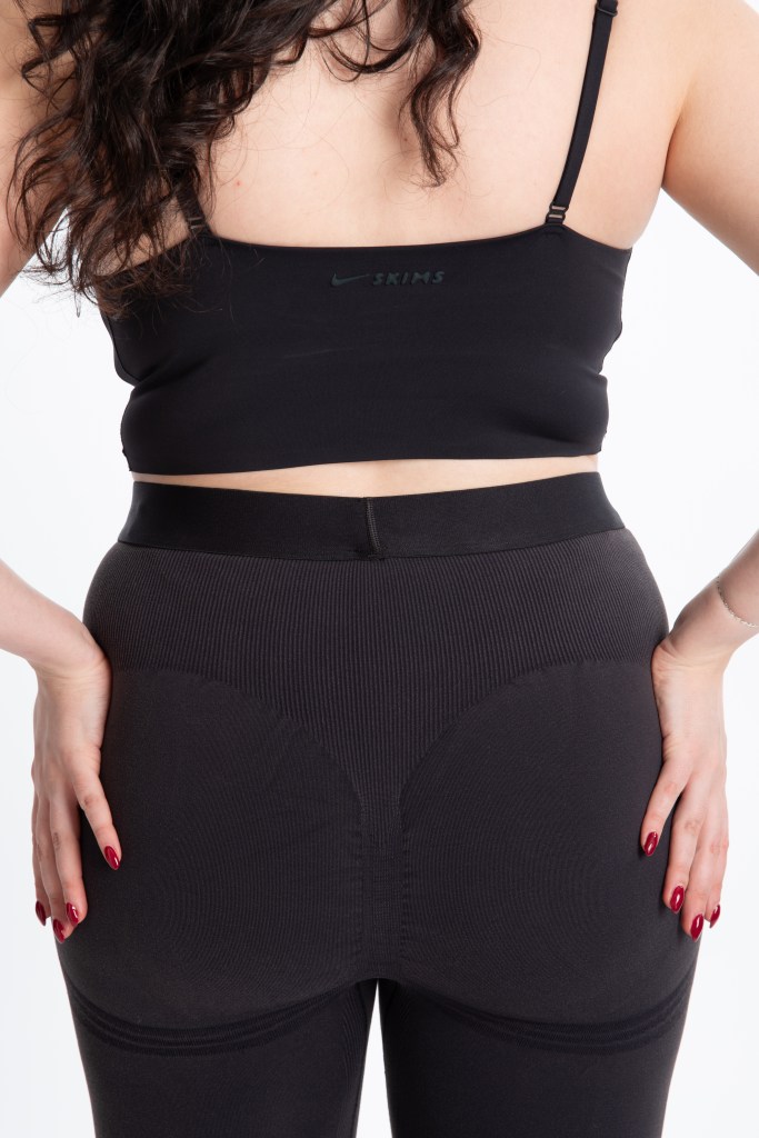 A woman wearing a Nike x Skims sports bra and leggings.