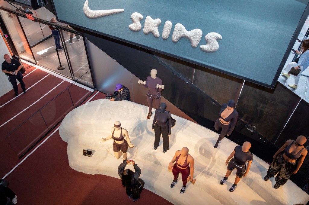 Shoppers observing Skims and Nike mannequins at a New York store.