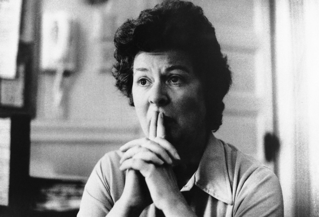 Sara Jane Moore in a close-up, looking away thoughtfully with hands clasped under her chin.