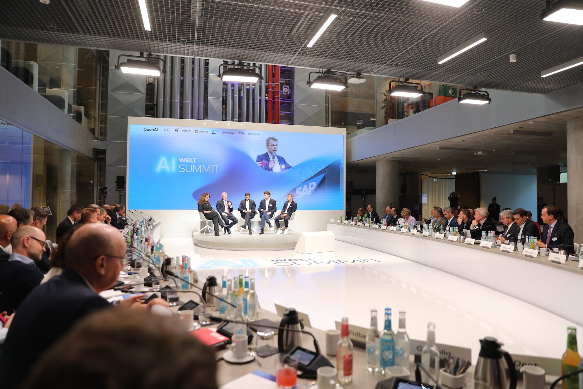 Technologists talk on a brightly lit stage.