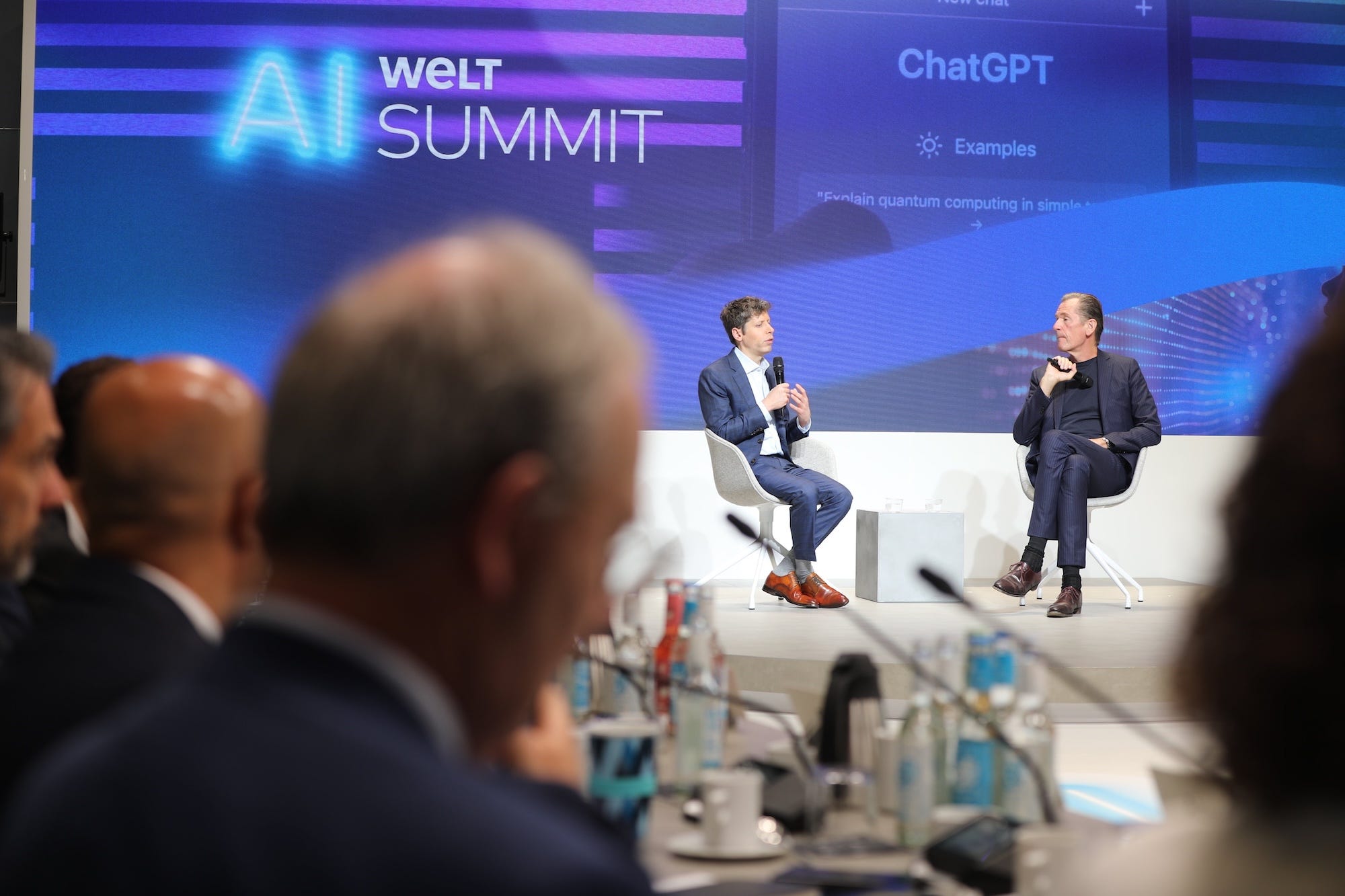 Sam Altman talks into a microphone as Mathias Döpfner listens.