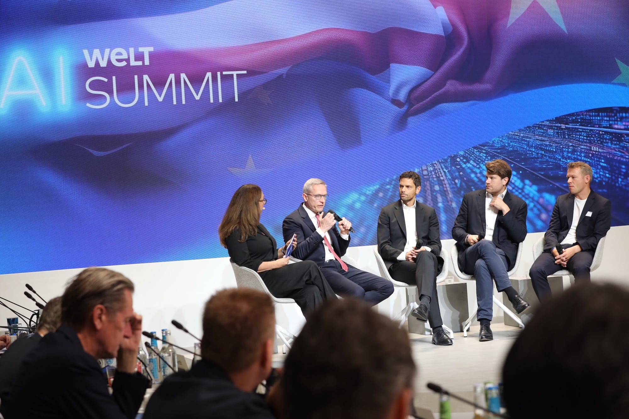Technologists participate in a panel discussion on a stage.