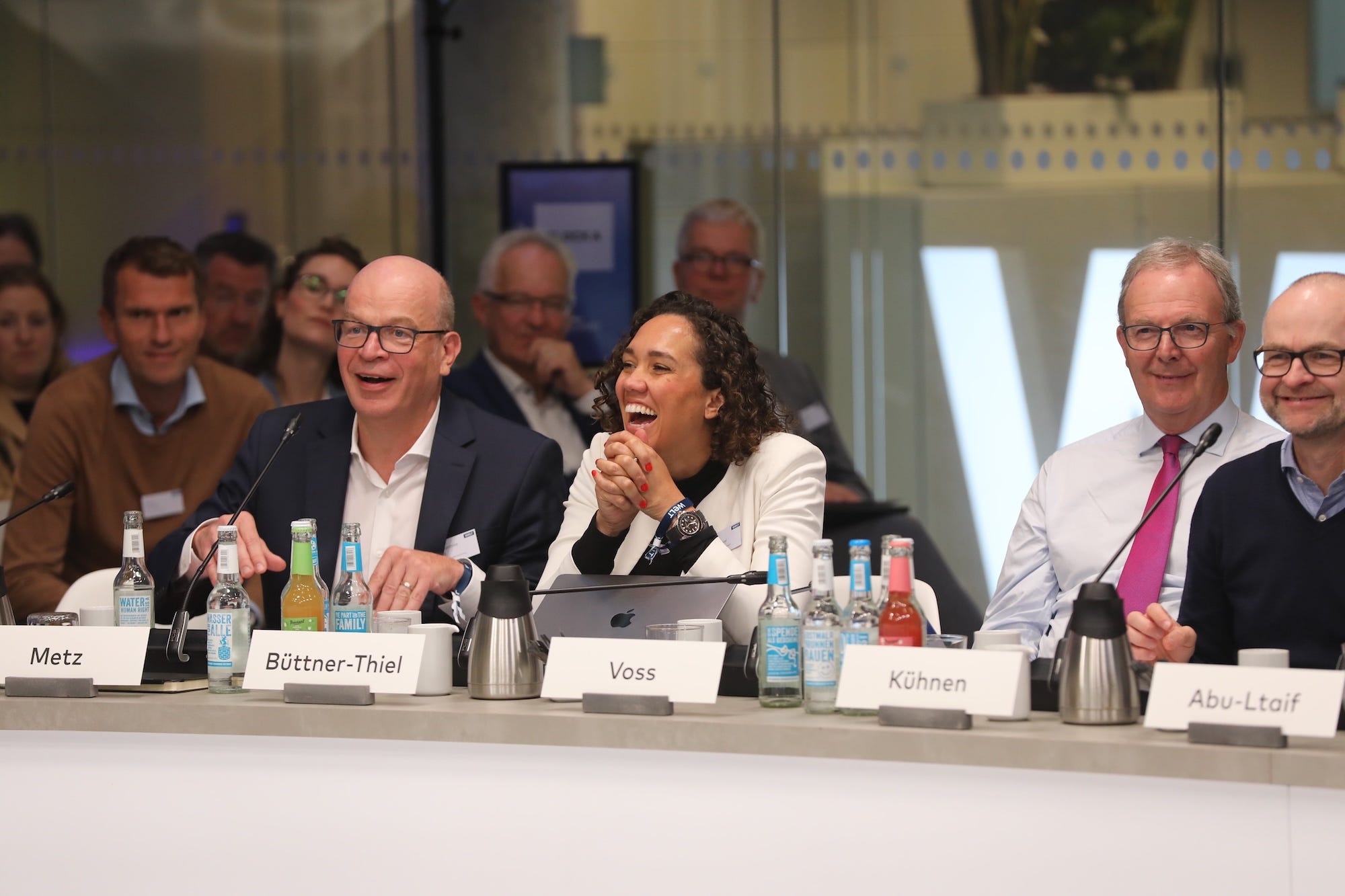 Professionals laugh massed around a conference table.