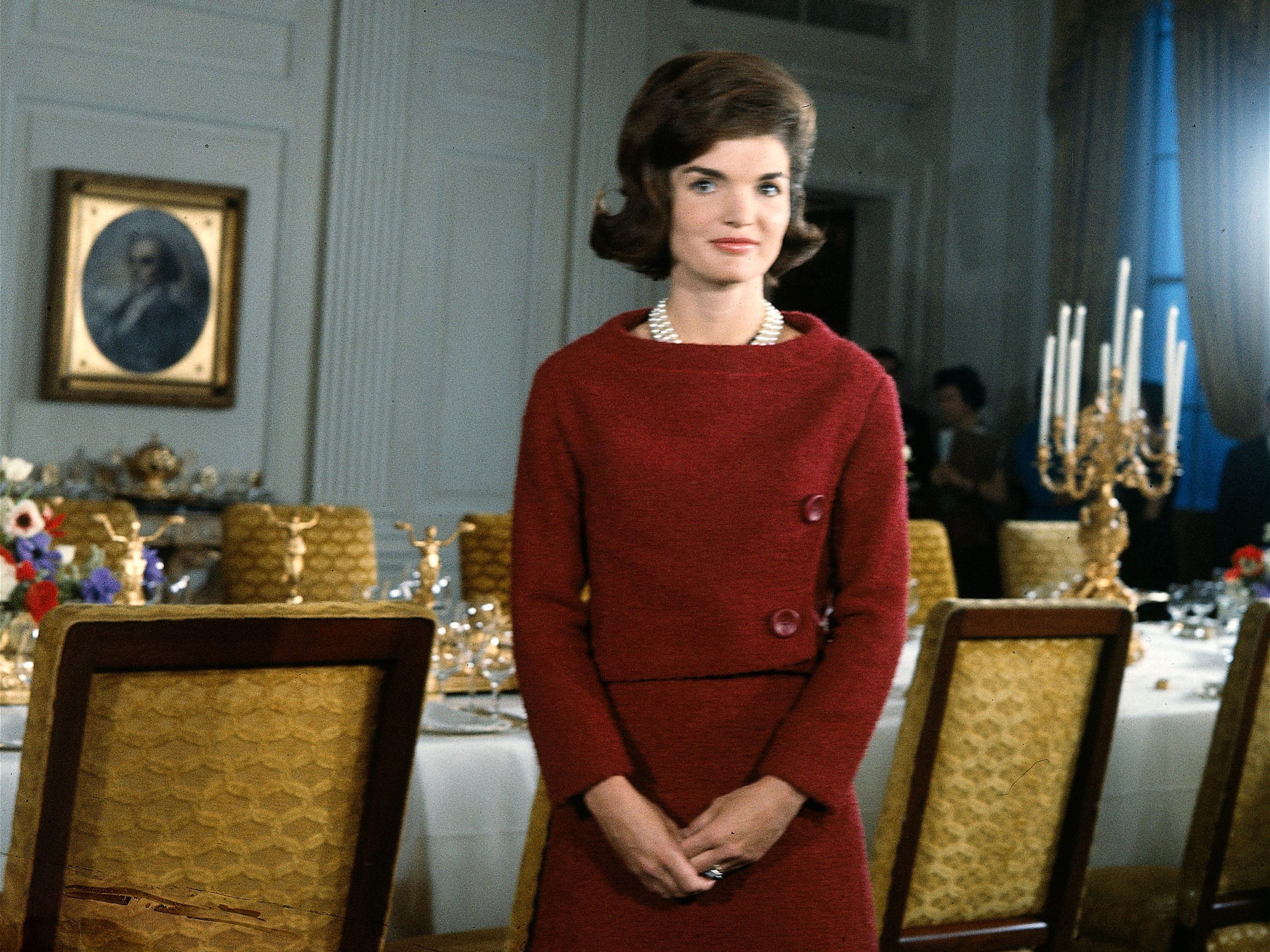 Jackie Kennedy stands in a dining room table inside the White House.