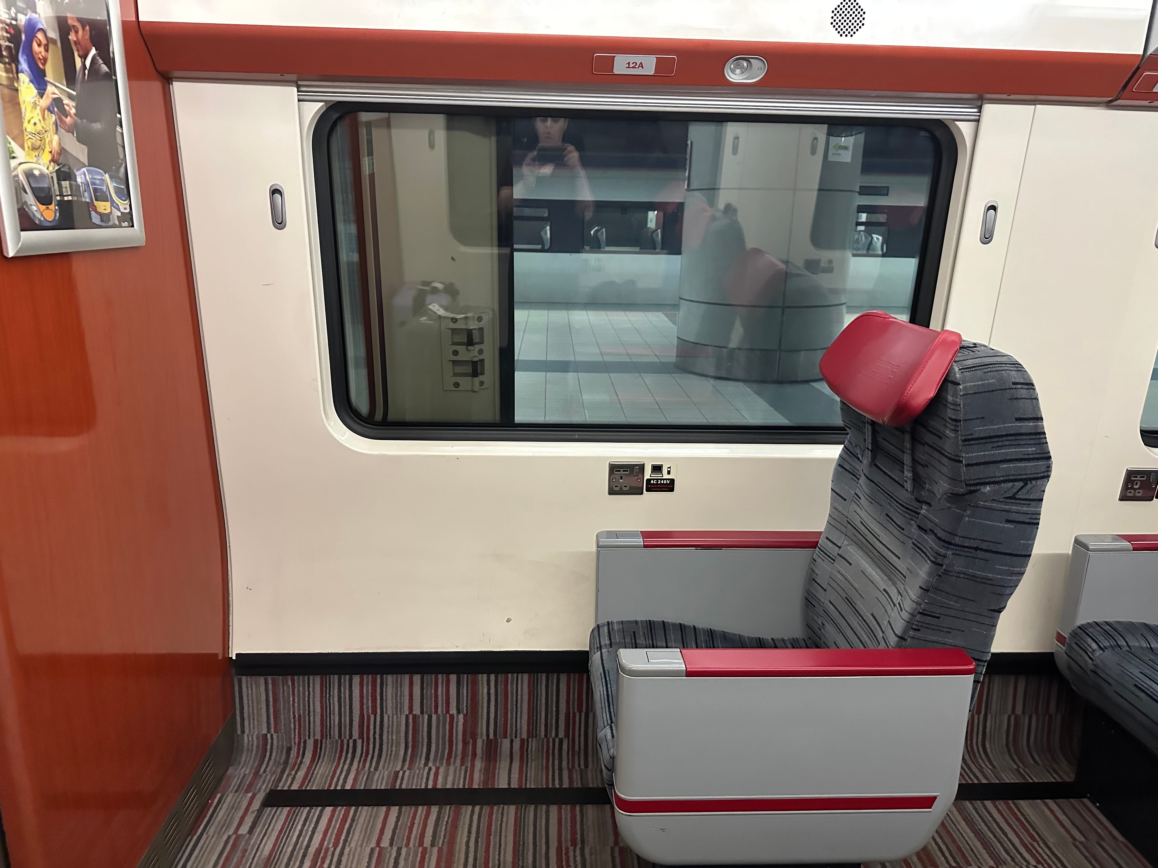 Single chair with high arms, fabric-covered with leather head rest facing wall on train
