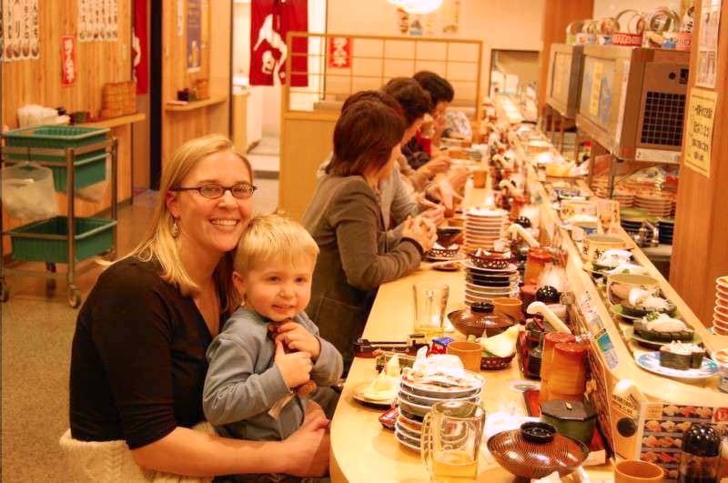 The author poses with one of her sons at a sushi restaurant in Japan.