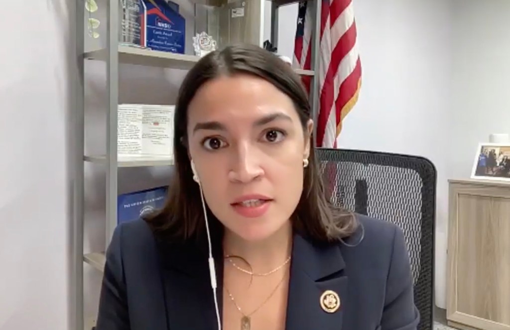 Alexandria Ocasio-Cortez speaking into wired earbuds during a virtual town hall.