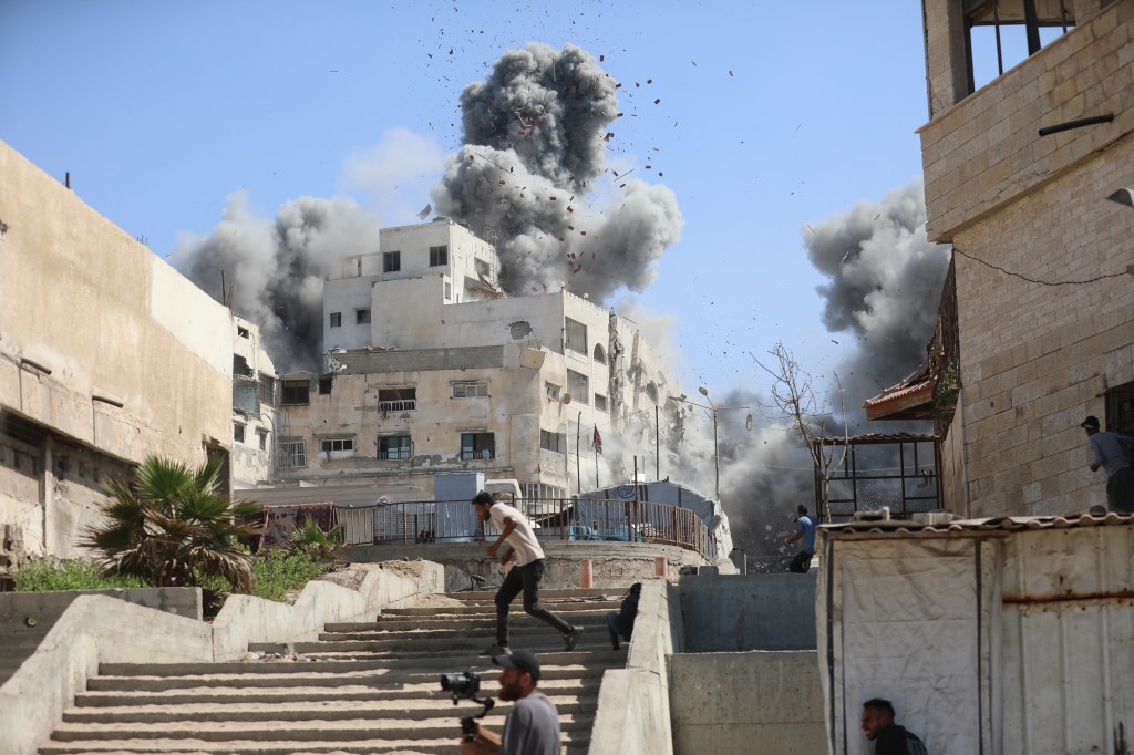 Smoke and debris filling the air after Israeli airstrikes hit multiple buildings in Gaza City.