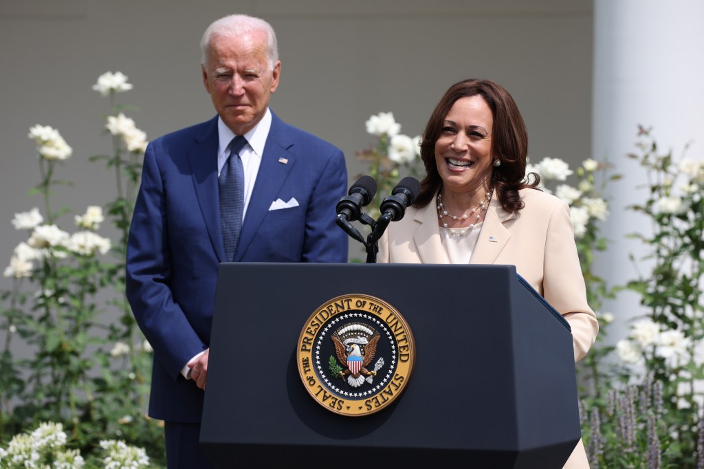 Kamala Harris delivers remarks at a podium in the Rose Garden, with Joe Biden standing behind her, to celebrate the 31st anniversary of the Americans with Disabilities Act.