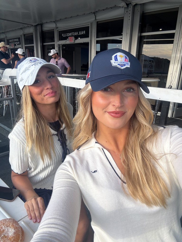 Golf influencer Cailyn Henderson and Madison Pool, wearing Ryder Cup hats, sitting at a table with a doughnut in front of them.