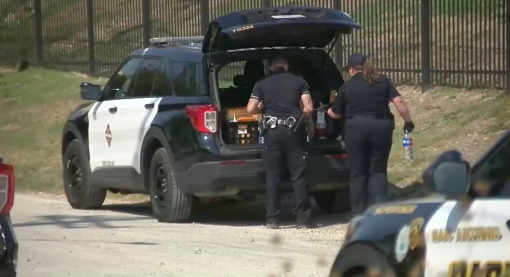 Police officers examining the back of a police SUV.