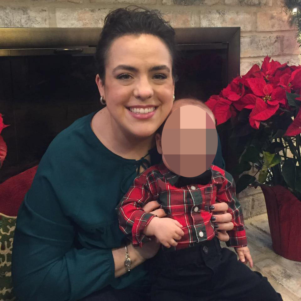 Victoria Anderson smiling while holding a baby whose face is blurred.
