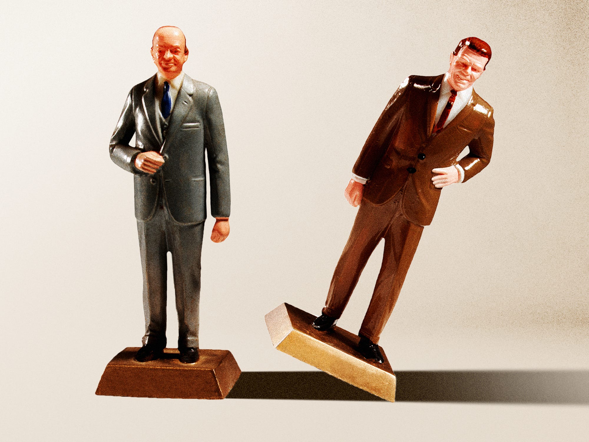 Two business men figures next to one another and on of them tipping over