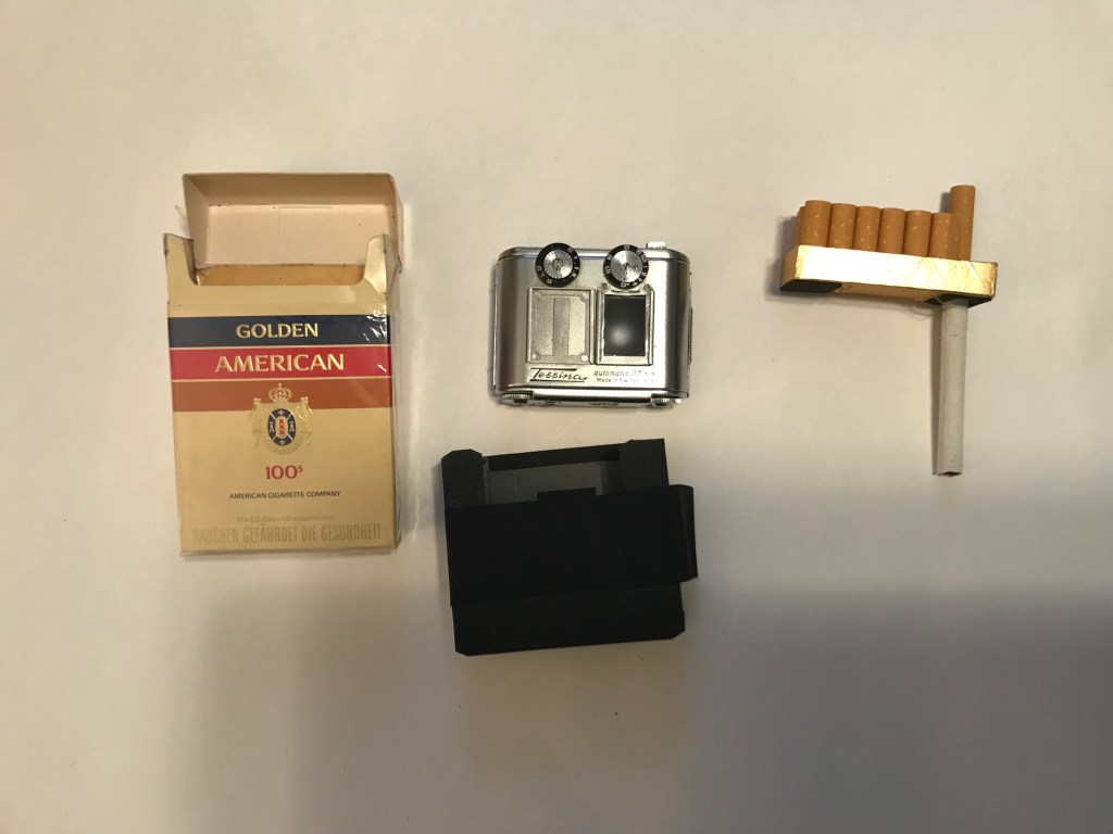 Golden American cigarettes, a Tessina camera, and a cigarette pack.
