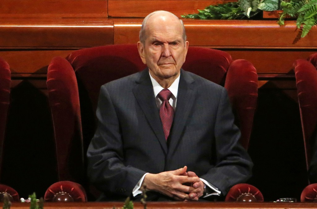Russell M. Nelson sits in a red velvet chair at a conference in Salt Lake City.
