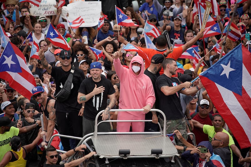 Puerto Rican artists Residente (L) and Bad Bunny (C R) join demonstrators in San Juan on July 25, 2019, one day after the resignation of Puerto Rico Governor Ricardo Rossello. - Puerto Rico's embattled governor announced his resignation late July 24, following two weeks of massive protests triggered by the release of a text exchange in which he and others mocked gay people, women and hurricane victims. 