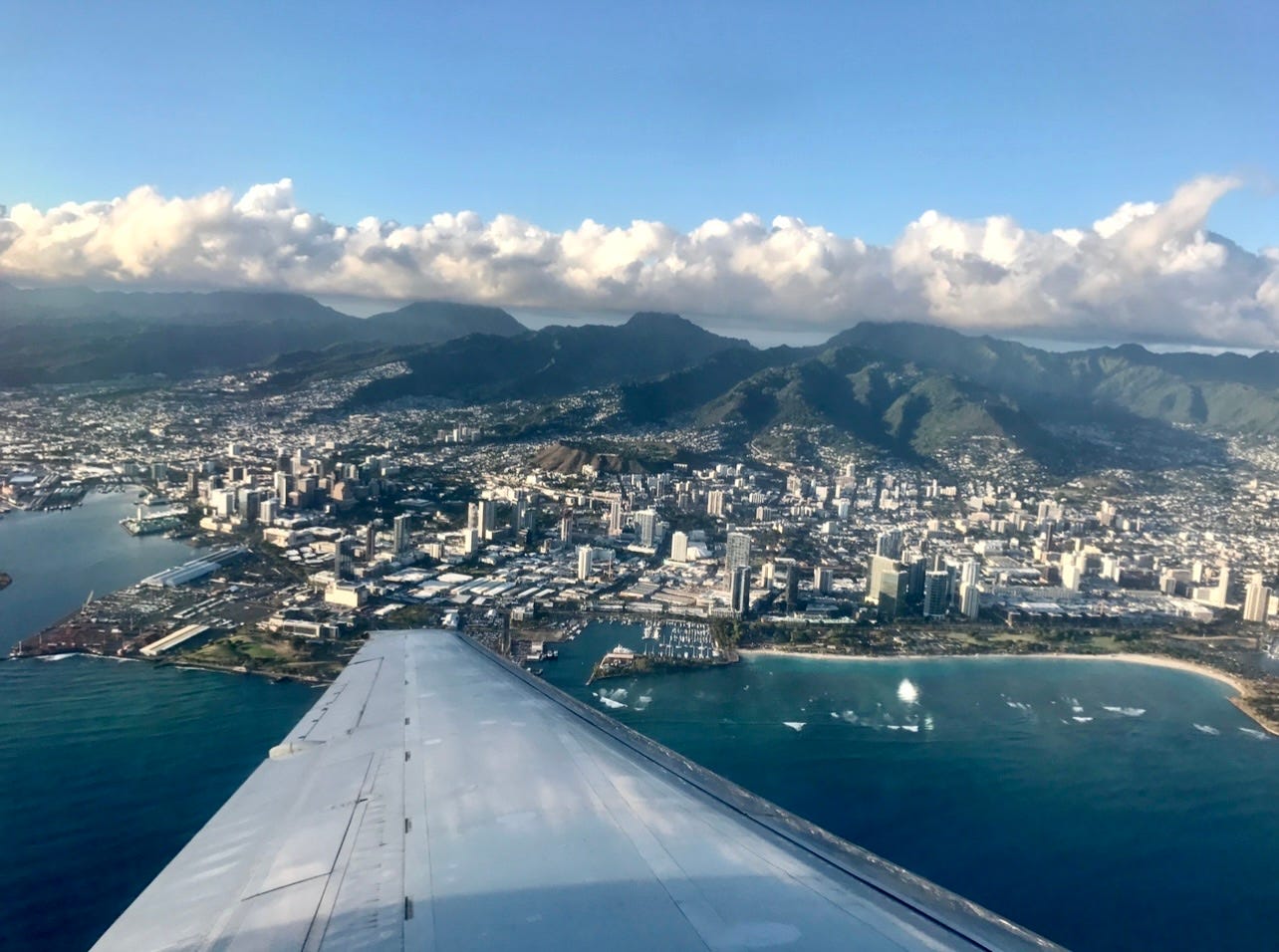 Aerial view of high-rise buildings, mountains in Oahu from plane