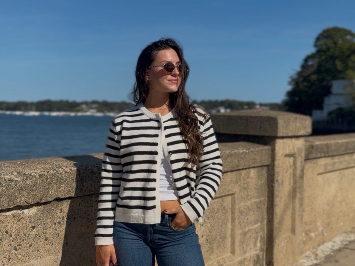 Amanda posing by a stone wall with the water behind her.