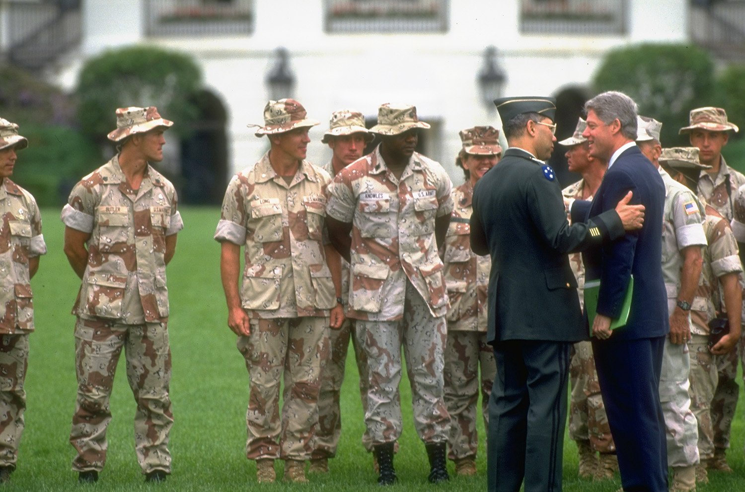 Bill Clinton, Colin Powell, and soldiers on the lawn of the White House.