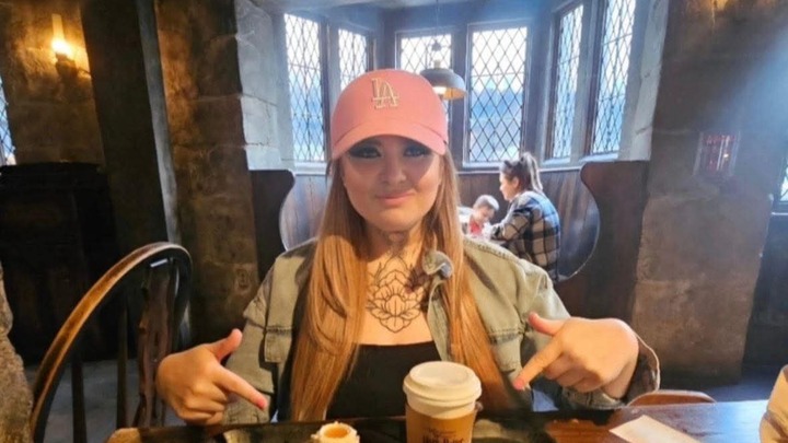 June Bunyan pointing to a drink in a restaurant.