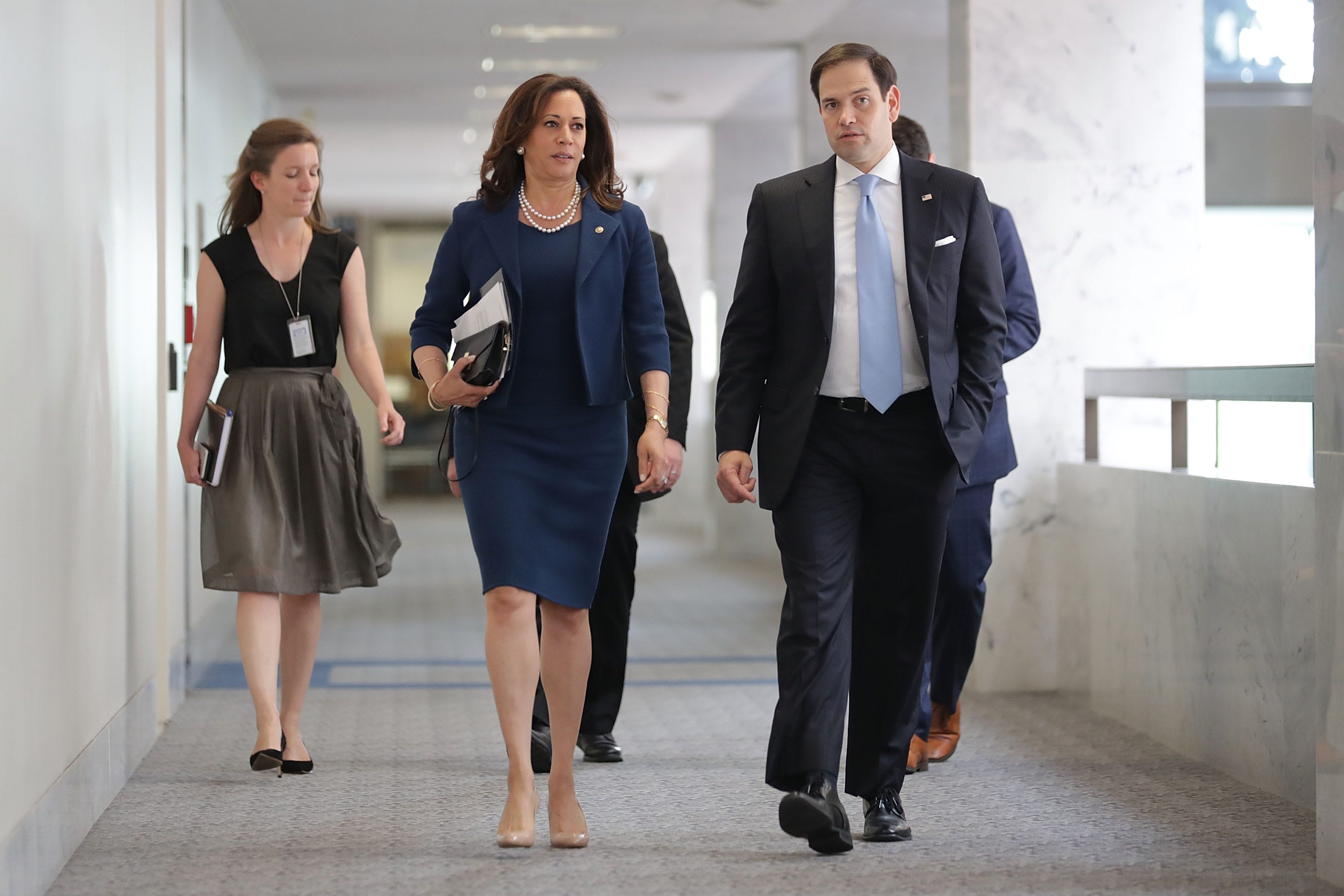 Kamala Harris and Marco Rubio walking together. She wears a navy dress and blazer.