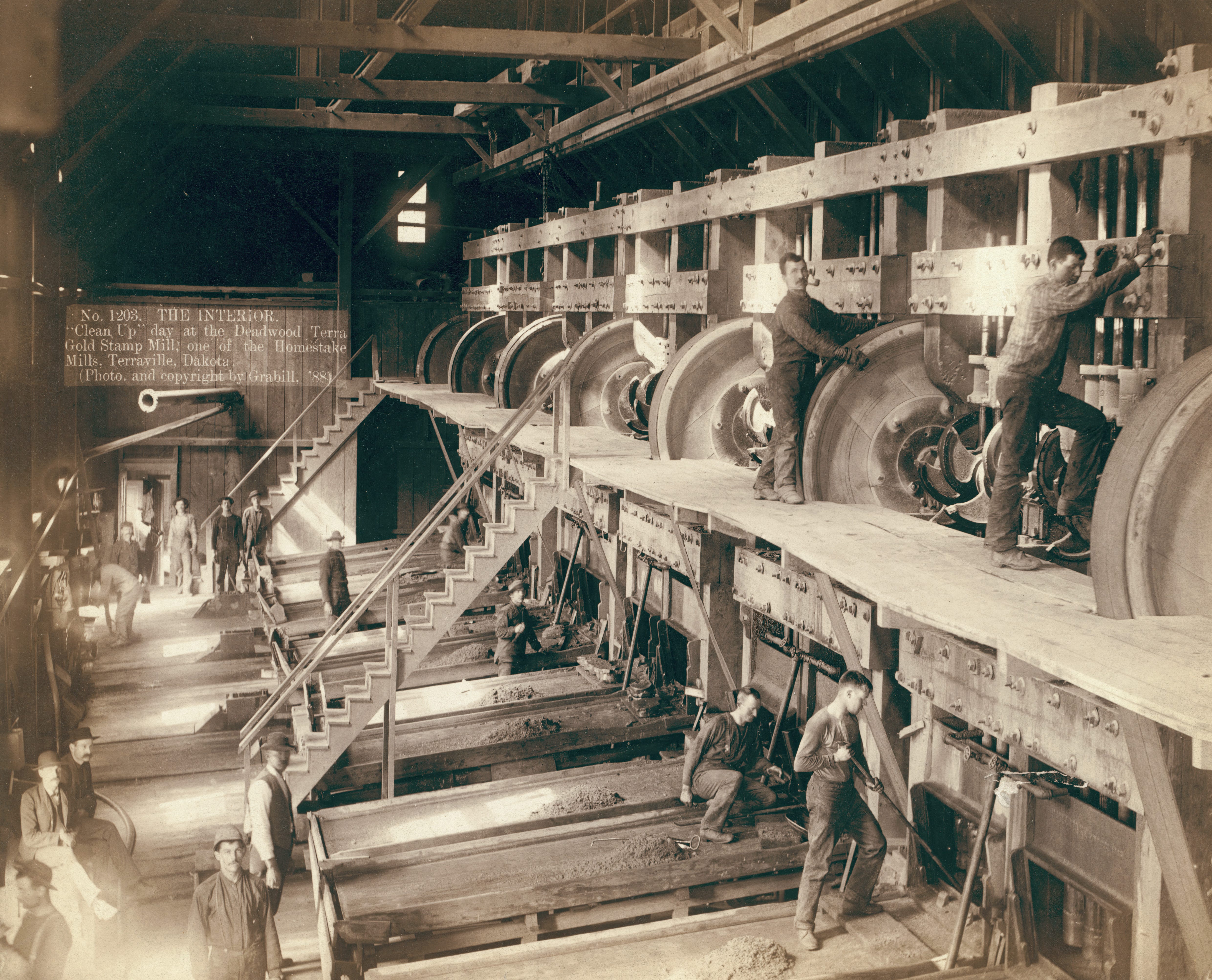 Several men clean equipment at a sawmill