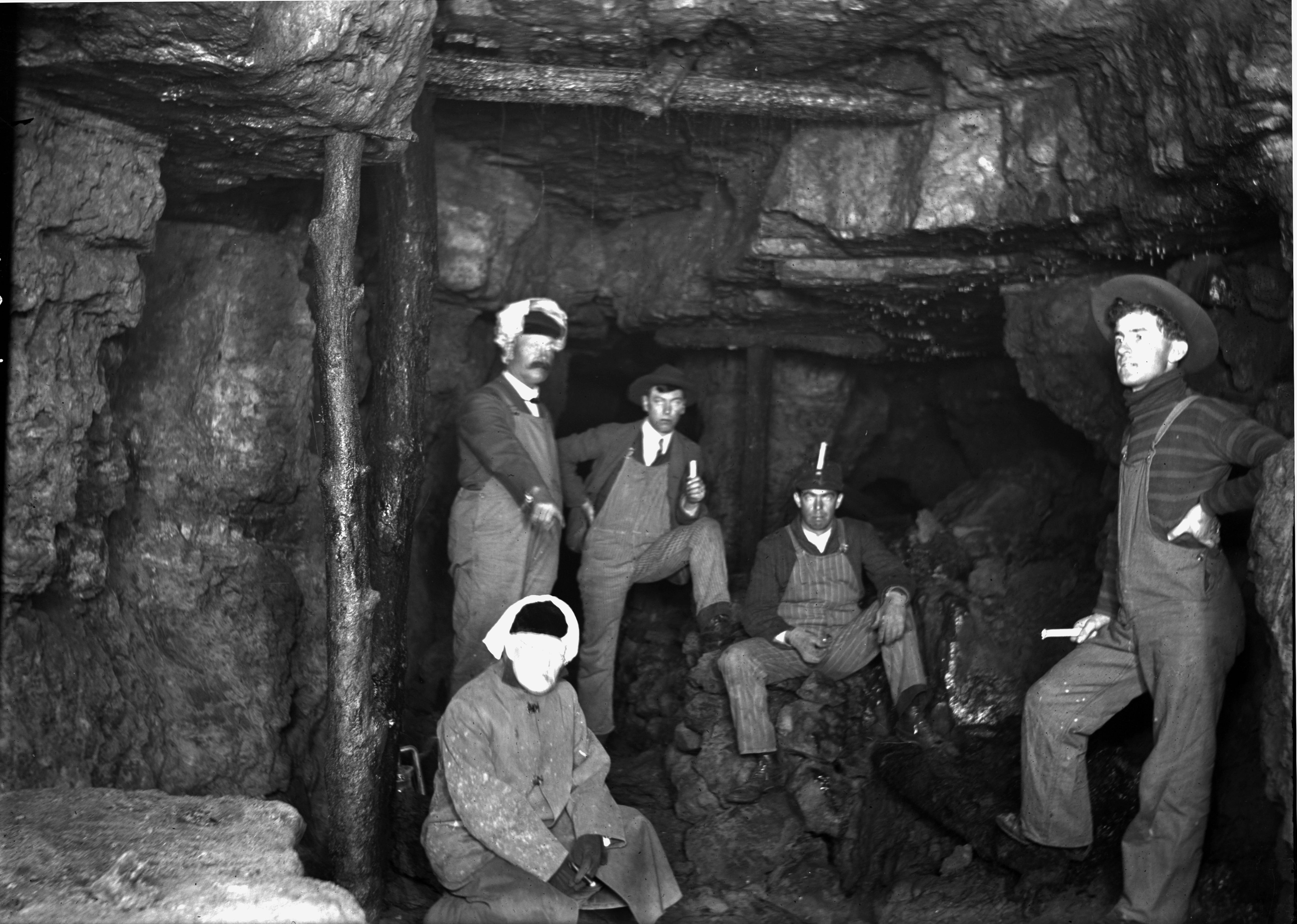 Several workers wearing overalls and hats in a mine
