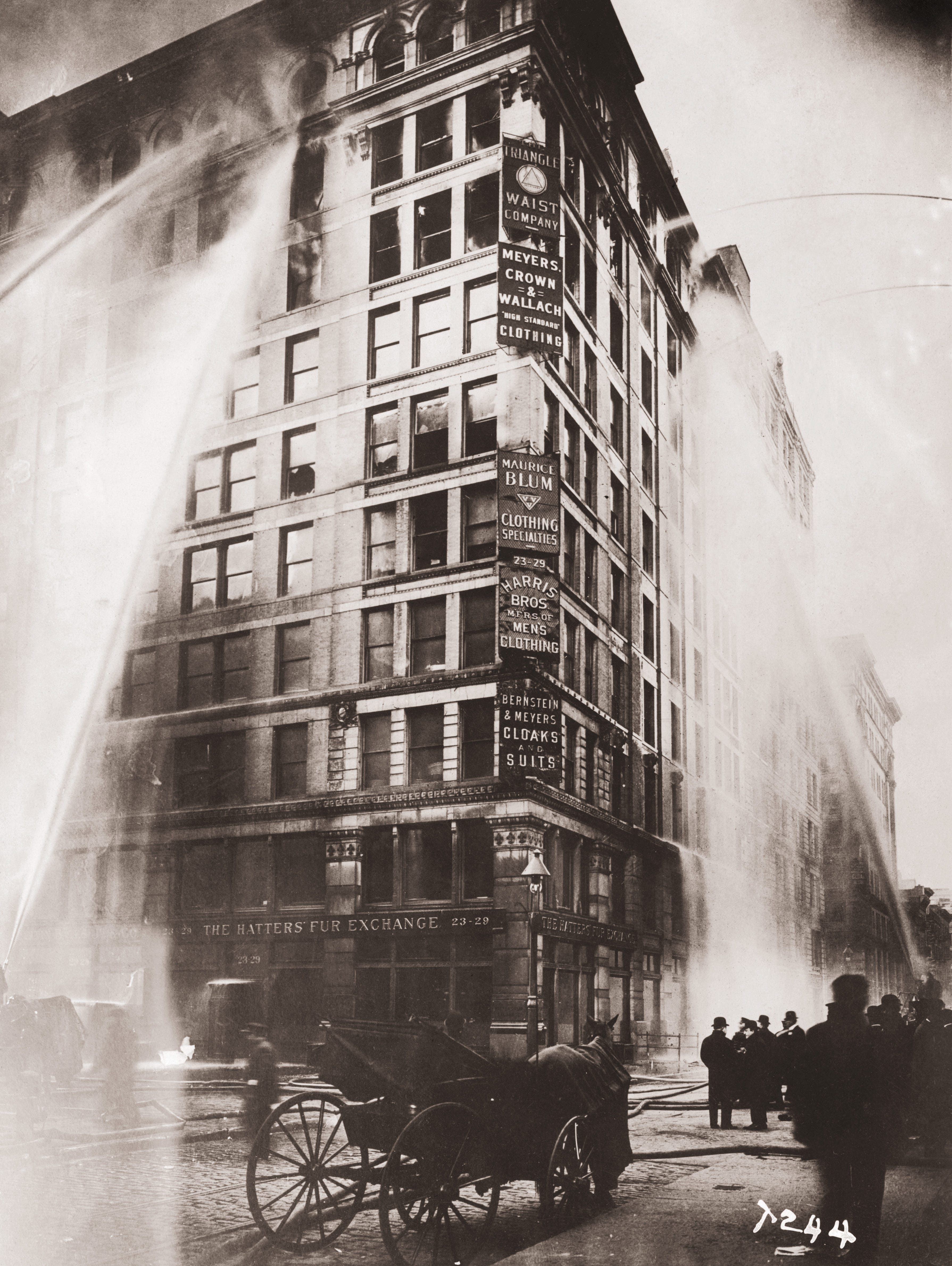 Fire hoses spray water on the upper floors of the Asch Building with a horse and carriage in front